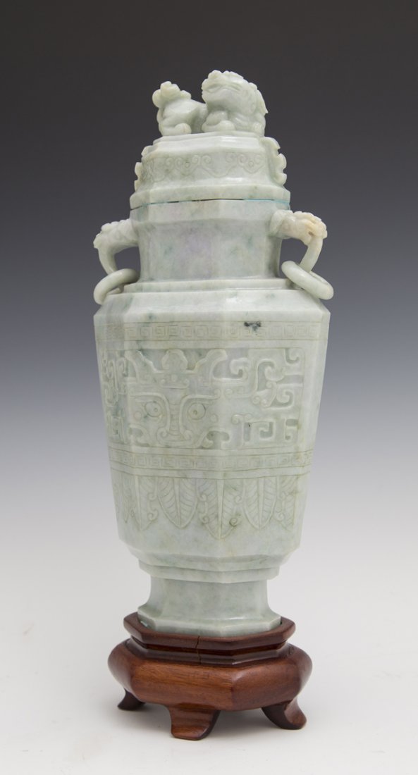 Large Oriental Jade Covered Footed Urn, 20th c., of: Large Oriental Jade Covered Footed Urn, 20th c., of tapered hexagonal form, the lid with a Foo lion surmount, the sides with Foo dragon ring handles and relief carving, on a carved hardwood stand, H.-