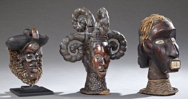 Group of Three African Carved Wooden Figures, one a: Group of Three African Carved Wooden Figures, one a mask with knotted string "hair," one a two sided figure with string "hair" on a wicker base; and one with a curled horn headdress on a wicker base, 