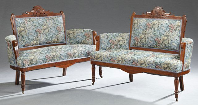 Pair of American Eastlake Carved Walnut Settees, late: Pair of American Eastlake Carved Walnut Settees, late 19th c., the incised scrolled crest over a rectangular upholstered back, above a trapezoidal bench seat, on ring turned tapered legs on casters, n