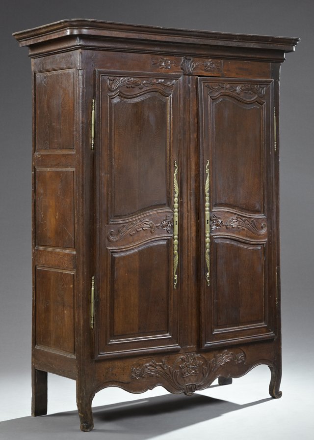 French Provincial Louis XV Style Carved Oak Armoire,: French Provincial Louis XV Style Carved Oak Armoire, early 19th c. the curved corner stepped crown over a foliate carved frieze above double fielded panel doors with long brass escutcheons and short b