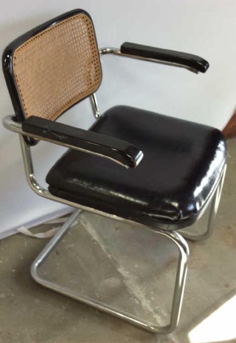 Marcel Breuer Style Chair: Arm chair with continuous steel tube frame, black Faux leather seat, black Ebony wood arms, , cantilevered frame. Caned back. Good Condition. Unknown date. Measures ht 32 inches width 19 inches depth