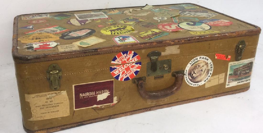 Vintage Oshkosh Circa 1930's Leather Trim Suitcase: Oshkosh Leather Trim Suitcase, circa 1930's, adorned in travel stickers from; Nairobi, Alaska, France, Italy, Kenya and more. Leather trim, peach fabric lining with tie downs and 3 working latches. Li