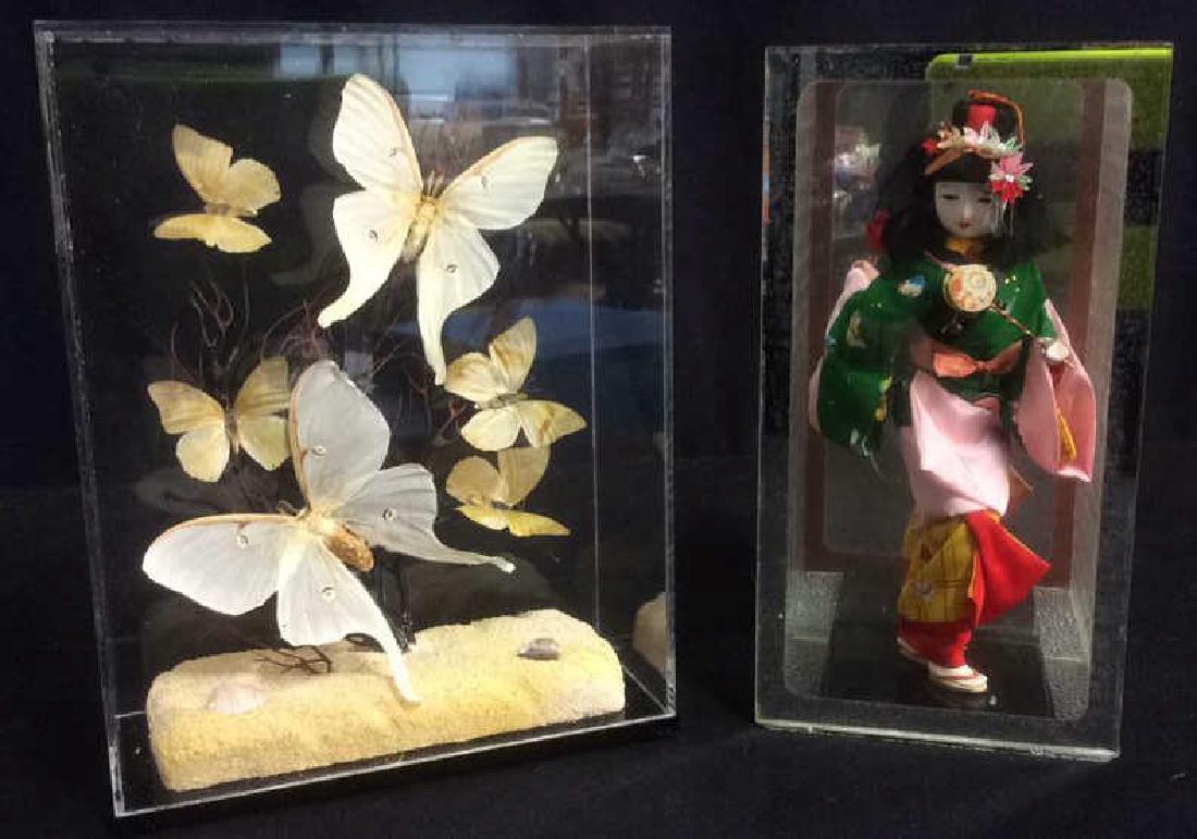 Vintage Plexiglass Cased Asian Sculpturals: Two vintage plexiglass statues. One depicting a group of butterflies; the other a woman in a kimono. The box containing the butterflies is approximately 8" x 3.5" x 10.5". The box containing the woman