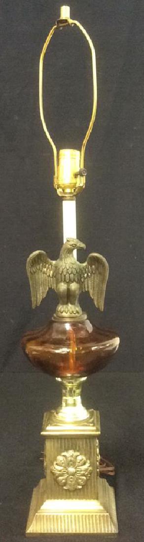 Ornate Pedestal Lamp with Eagle: Ornate pedestal table lamp, possibly brass with amber glass font, eagle and rosette decorations. Measures approximately 30 1/2 inches in height including harp and 6 inches in width.