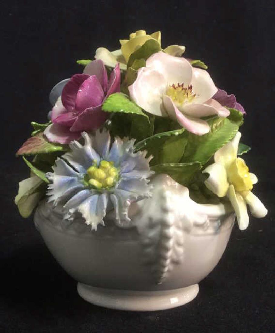 COALPORT Bone China Capodimonte Decor: Bone China basket with bachelor buttons, violas,rosettes and more. One small petal chip noted. Measures approx 4 1/2 inches tall by 4 inches, marked on underside for COALPORT