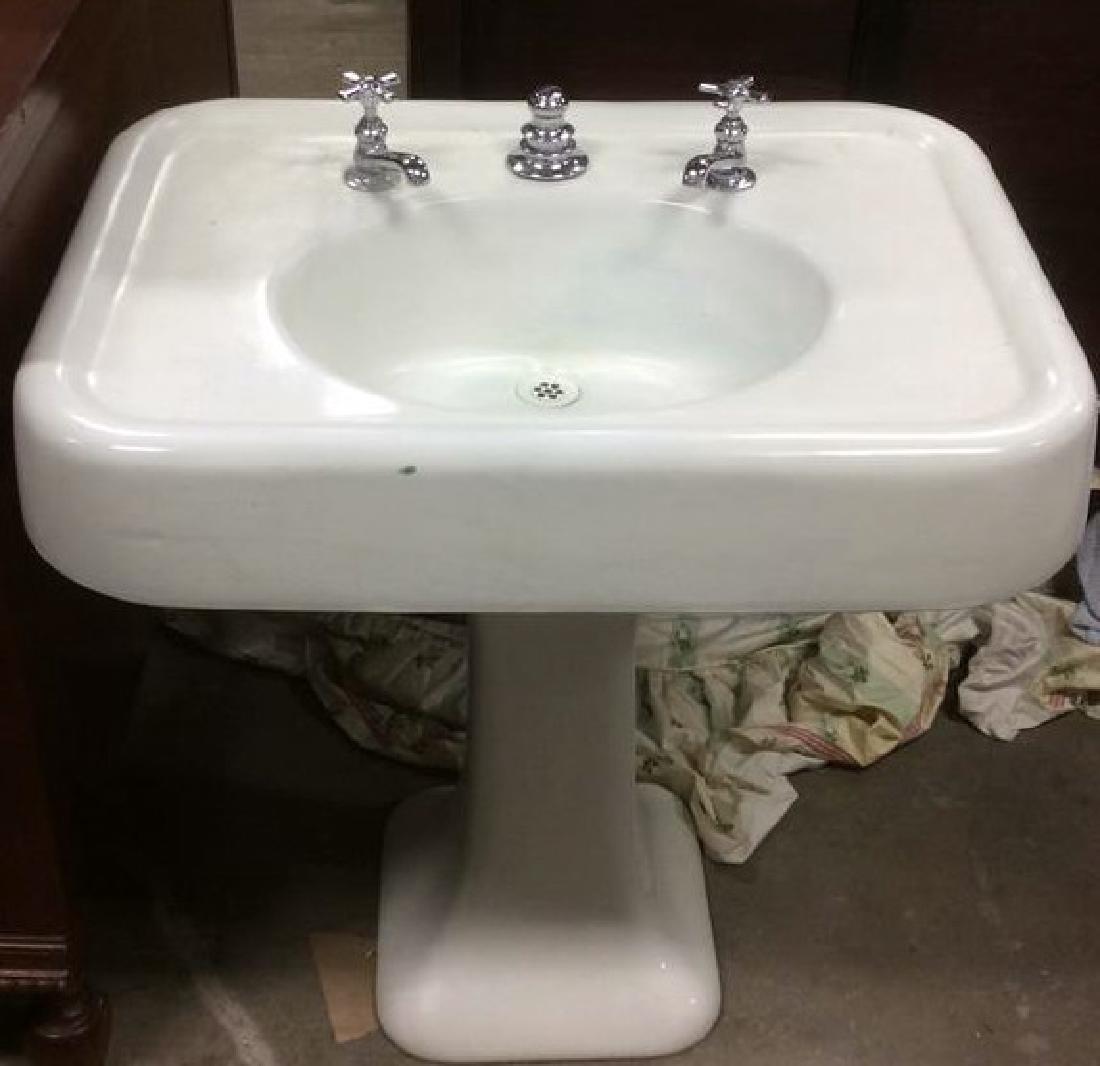 White Porcelain Cast Iron Pedestal Lavatory Sink: White Porcelain Sink with silver toned chrome handles. Cast iron pedestal base. Rectangular top with rounded corners and oval basin Measures approx 31 inches tall 30 inches wide 22 inches deep.