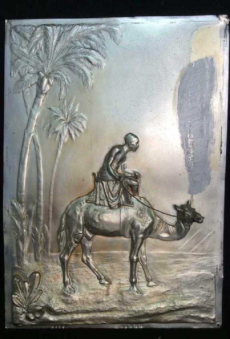 KUNSTANSTALT WMF GEISLINGEN Plaque Boy on Camel: KUNSTANSTALT WMF GEISLINGEN Relief Plaque Boy on Camel. Dimensional relief silver toned metallic plaque, Repoussee, stamped beneath artwork as KUNSTANSTALT WMF GEISLINGEN. Also marked as 8015, 38x26, 