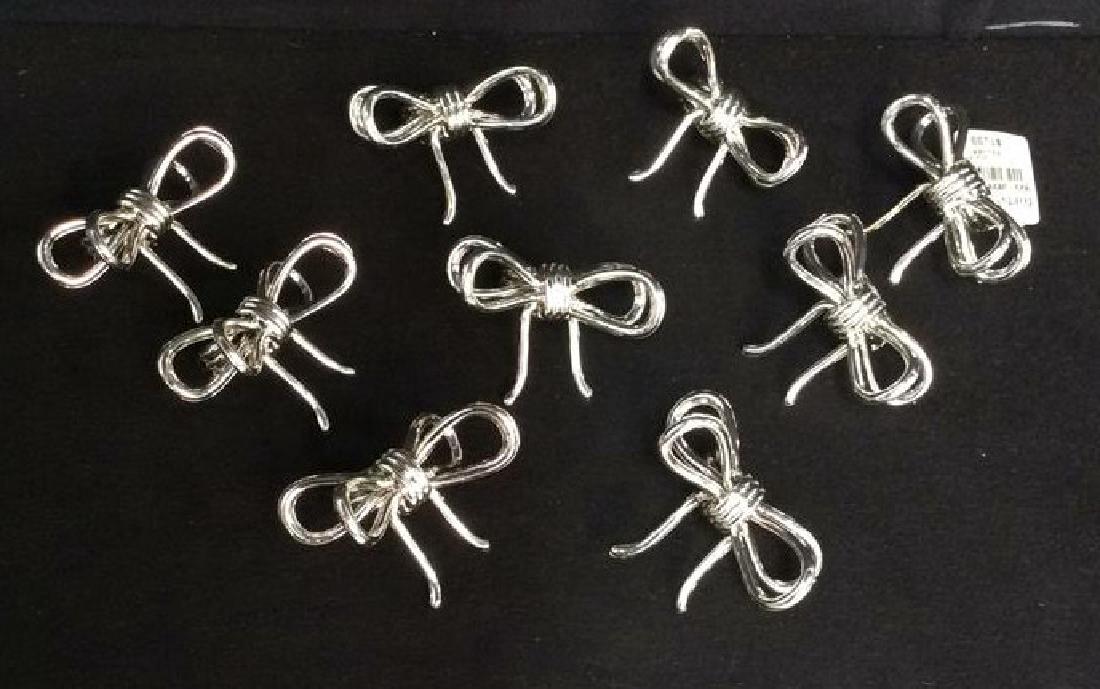 Set 9 Silver Toned Painted Bow Napkin Rings: Set 9 Plastic Silver Toned Painted Bow Napkin Rings. Marked on tags as FORTUNOFF. Individual pieces measure approx 3 in in diameter.