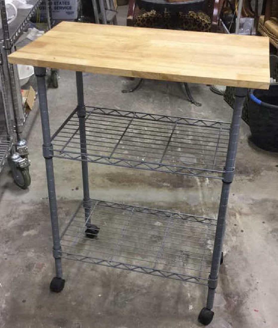 Kitchen Island On Wheels With Shelving.: Kitchen Island On Wheels With Shelving. Grey metal frame with two shelves, a wooden top, and black lockable wheels. Some surface scratches to wooden top and water stain. Measures approx 34 inches h x 