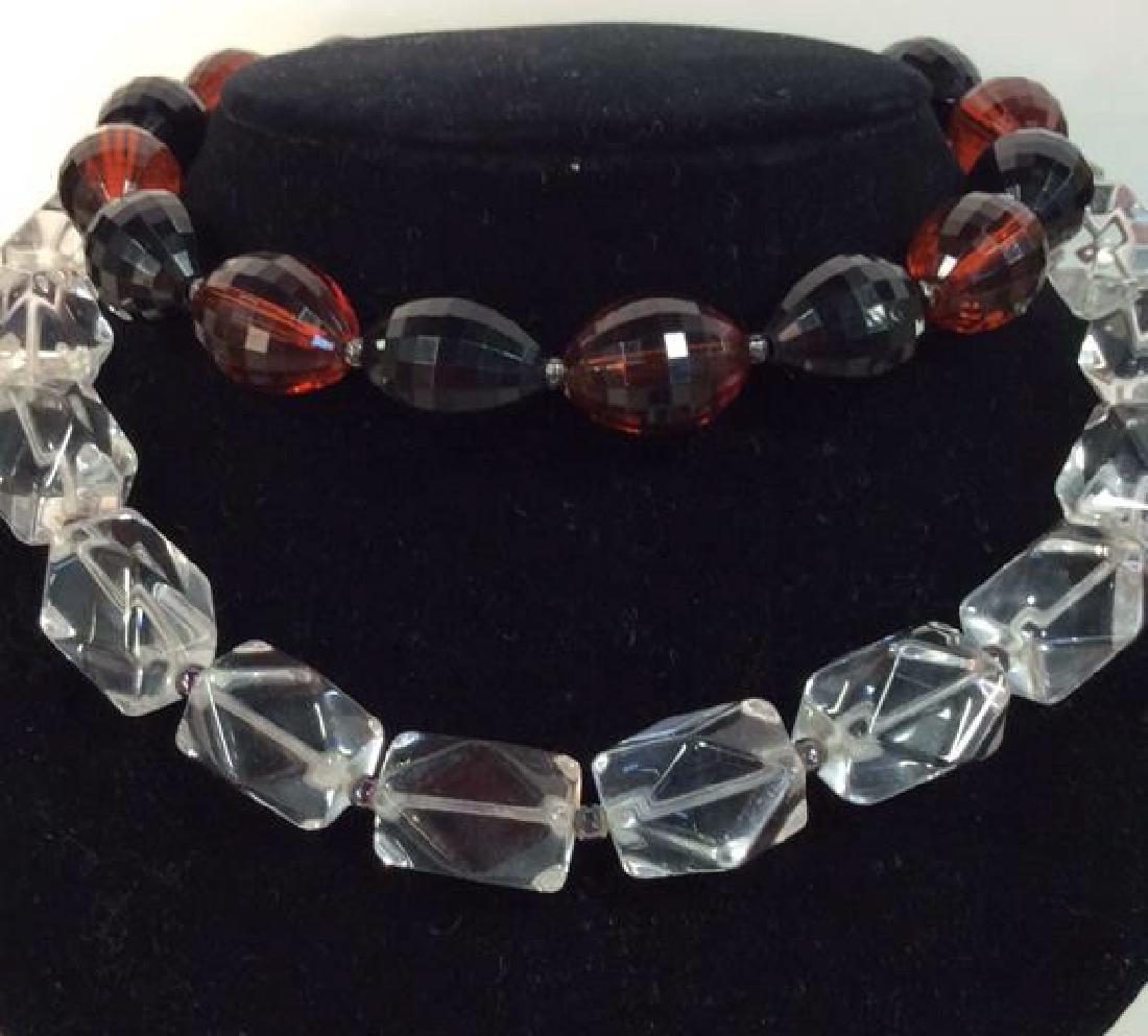 Lot 2 Women’s Costume Jewelry Necklaces: Lot 2 Women’s Costume Jewelry Necklaces. Possibly bakelite or plastic beads. One necklace features clear beads with iridescent toned spacer beads. One necklace features two rust toned and black tone