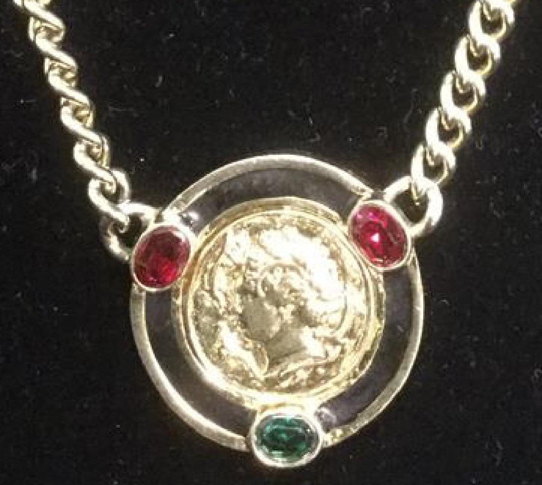 Vintage Versace Era C 80-90's Necklace: Gold Plated metal with enamel and rhinestones. Gold toned medallion with romanesque relief detail. Contains 1 green and 2 ruby toned rhinestones. Enamel is black toned. Measures approx 16 inches. Vint