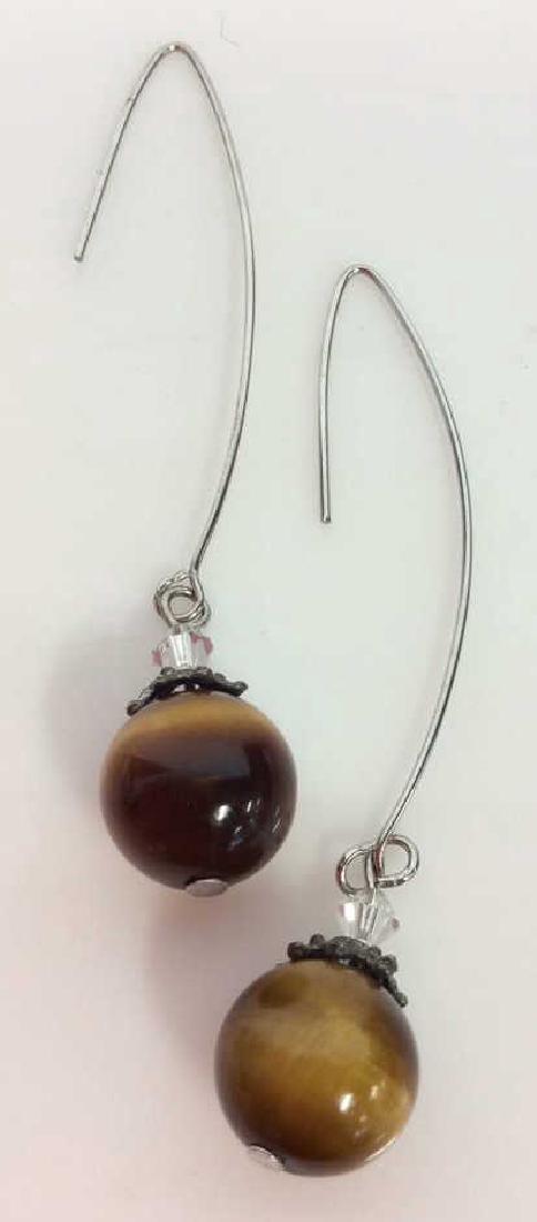Natural Stone Tigers Eye Earrings: Natural Stone Tigers Eye Earrings. Pair of silver toned metal earrings with round polished natural stone bead, appears to be tigers eye. also features dark toned metal filigree detail and rhinestone b