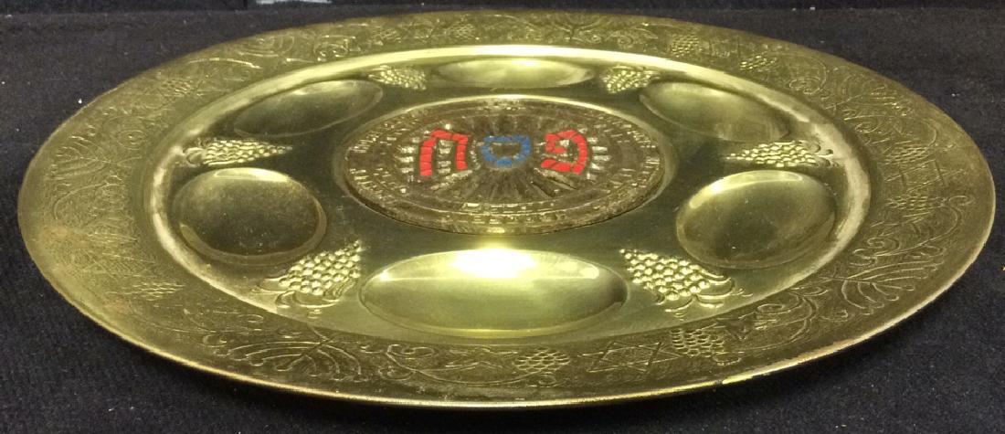 Gold Toned Metal Judaica Plate: Plate is gold toned with intricate relief detail. Includes relief images of Menorahs, star of David & grapes. Contains 6 sections for food. Sections are labeled egg, horseradish, parsley, haroseth, bi