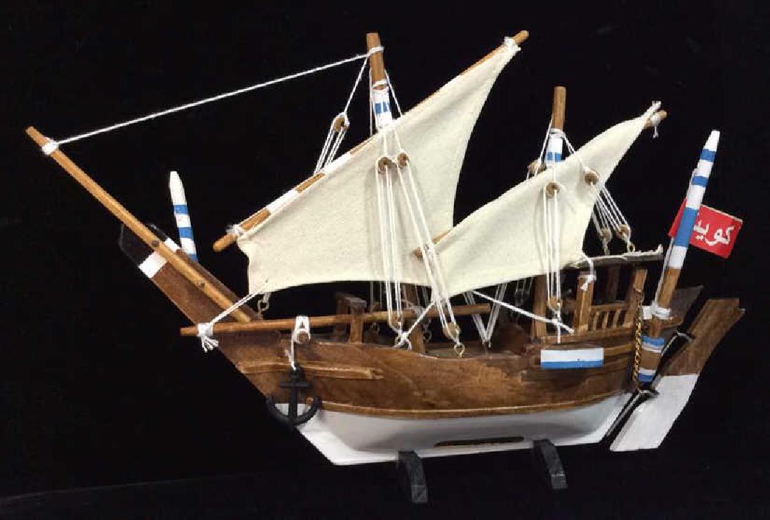Baghlah Arab Sailing Vessel Model: Baghlah Arab Sailing Vessel Model. Wooden ship model with canvas sails and details and plastic anchor, attached to a small wooden stand. Appears to have Arabic script on sticker and paper tag. Measure