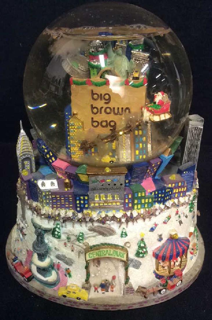 Snow Globe Music Box New York City: Snow globe is possibly SANKYO. Contains multi toned figural details. Contains text that reads BIG BROWN BAG, CENTRAL PARK. Appears to Depict New York City in the Winter. Measures approx 8 inches tall 