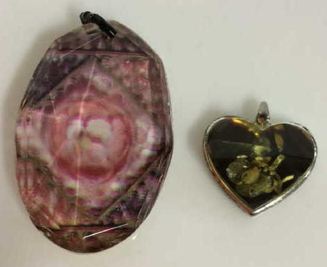 Lot 2 Resign Pendants with Floral Designs: Lot 2 Resign Pendants with Floral Designs. One heart shaped pendant with silver toned metal base and asymmetrical poured resign pendant with what appears to be natural flower petals. One pendant, resi