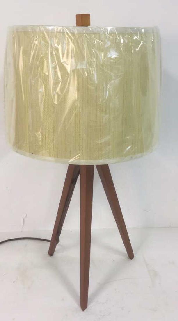 Wooden Tripod Lamp With Textured Fabric Shade: Wooden Tripod Lamp With Textured Fabric Shade. Brown toned wooden tripod base with brown toned metal hardware, textured fabric shade of light beige and green design, and light wooden square finial. Pl