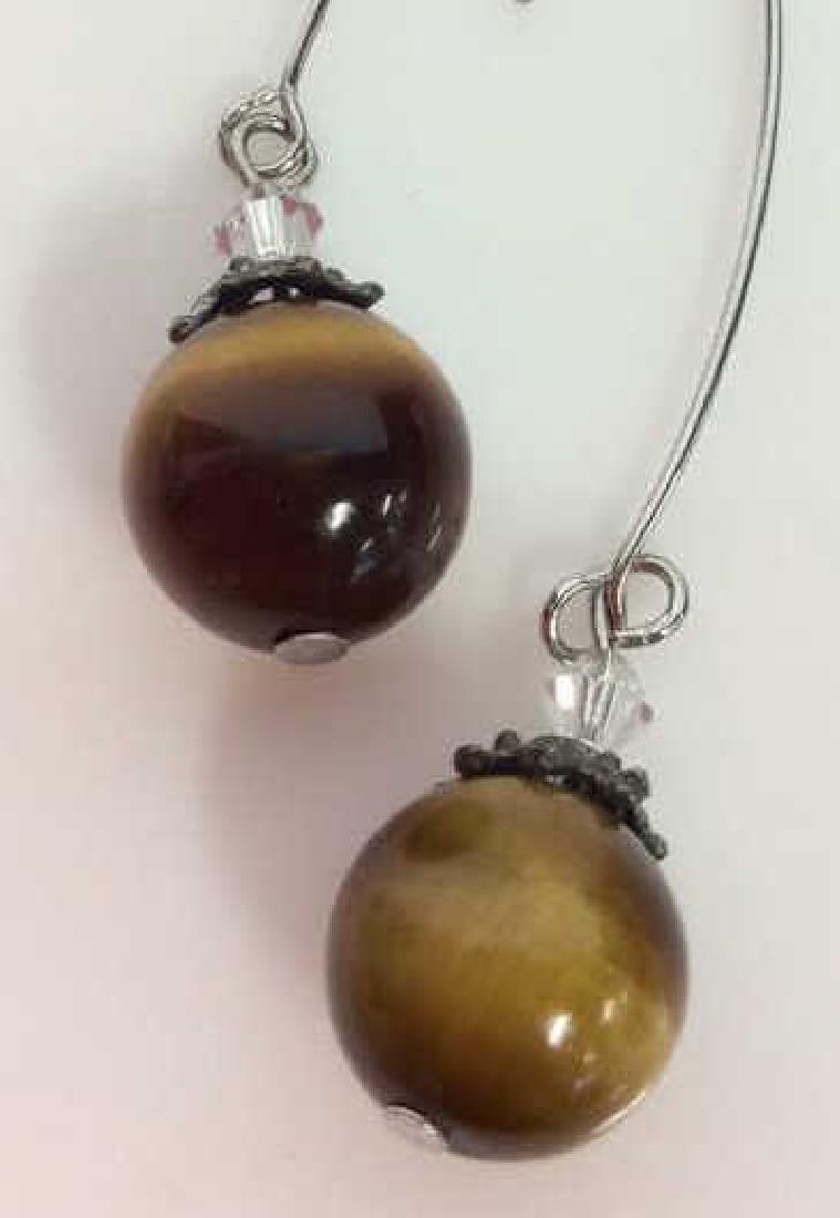 Natural Stone Tigers Eye Earrings: Natural Stone Tigers Eye Earrings. Pair of silver toned metal earrings with round polished natural stone bead, appears to be tigers eye. also features dark toned metal filigree detail and rhinestone b