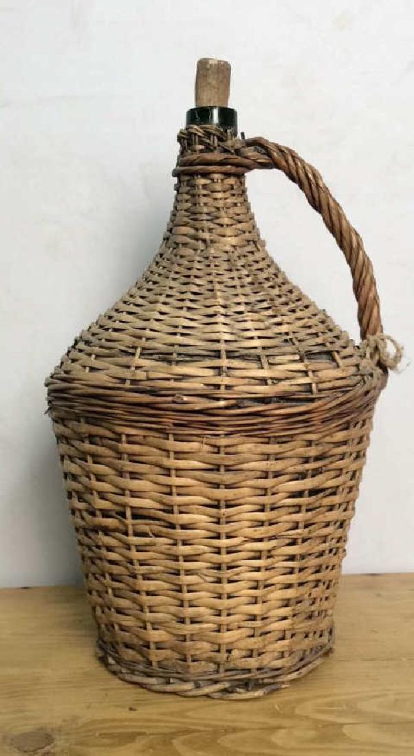VIntage Whicker Basket Wrapped Jug: Whicker Basket Wrapped Jug. Jug figural wrapped in tan whicker details, handled Glass jug. Rustic home decor. Some wear and discoloration to whicker. Measures approx 21 in tall by 11 in in diameter.