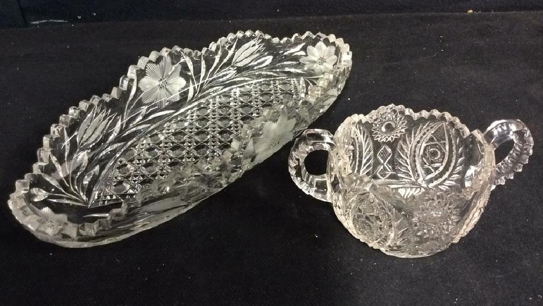 Lot 2 Cut Crystal Tabletop Accessories: Includes one toothed oval shaped display piece with frosted floral relief detail. And one toothed double handle cup. Measures approx 13 inches long 5.5 inches wide. Oval shaped display piece has chips