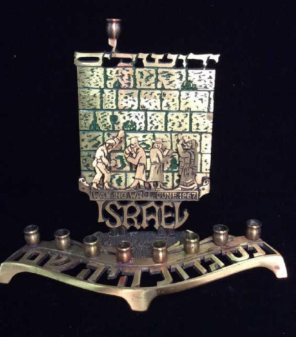 OPPENHEIM Vintage Wailing Wall Menorah: OPPENHEIM Vintage Wailing Wall Menorah. Dimensional depiction of men in front of the Wailing Wall, text reads Wailing Wall June 1967, Israel. Brass toned metal menorah. Vintage Israeli Judaica. Marked