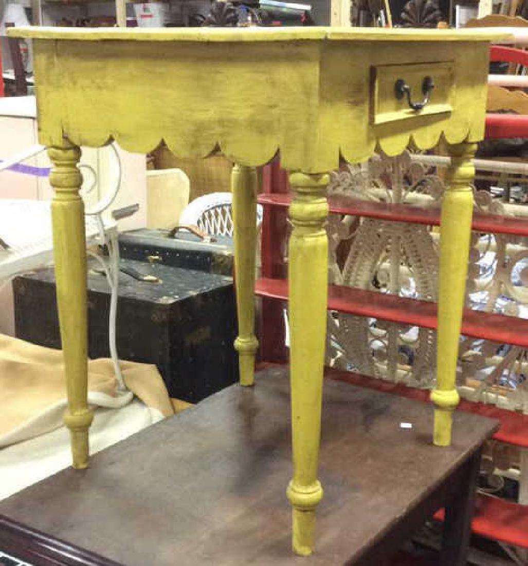 Yellow Mustard Toned Wooden Table: Vintage possibly antique Mustard toned wooden table contains repeating rounded design beneath the drawer with a black toned handle. Contains legs with rounded legs with some ware and scratches. Measur
