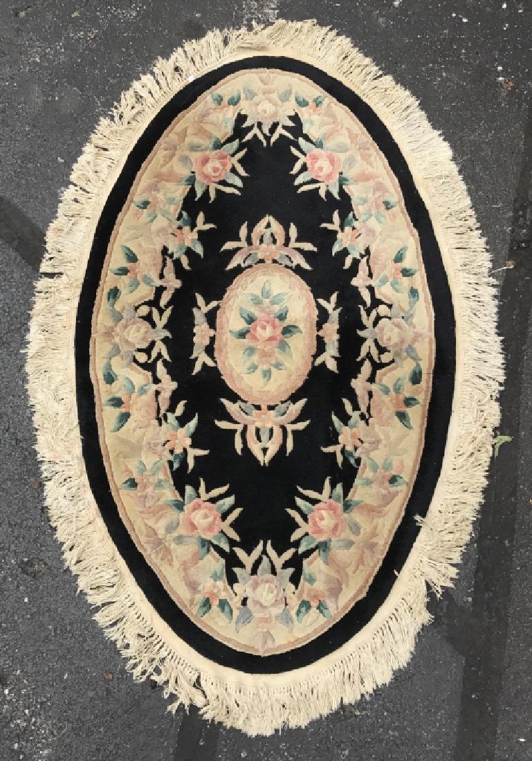Poss Handmade Wool Pile Oval Rug: Poss handmade wool pile oval shaped rug contains gold toned fringes with black base and various colored floral detail, including red, green, purple, and blue. The color contains some fading. measures 