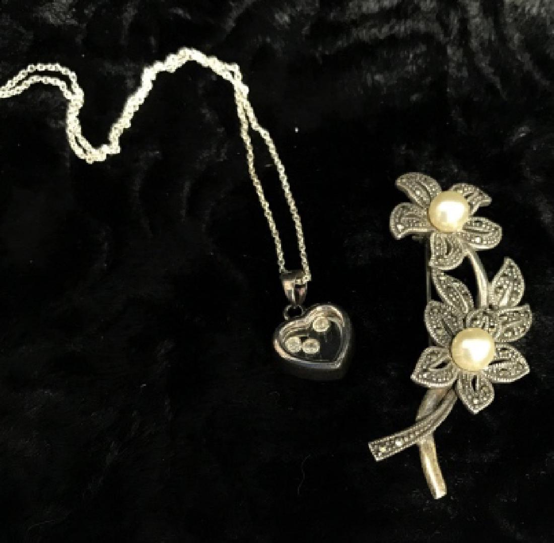 Lot 2 Sterling Silver Women's Jewelry: Lot 2 Sterling Silver Women's Jewelry. One floral sterling silver brooch pin with marcasite stones and two pearls, possibly natural possibly faux. Measures approx 2 in long by 1 in wide. Marked in rev