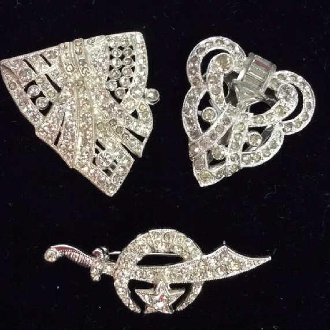 Lot 3 Vintage/Antique Rhinestone Jewelry: Lot 3 Vintage/Antique Rhinestone Jewelry Pair of shoe clips pins with rhinestone design, art deco inspired. One brooch pin with sword and moon motif, marked on reverse as ORA. Pieces measure approx 1 