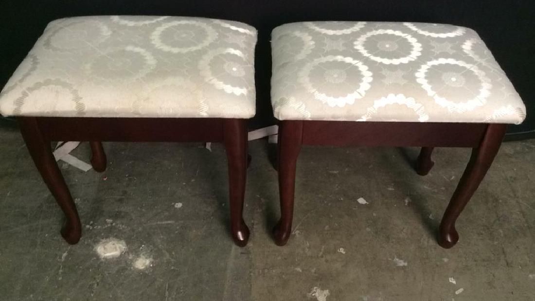 Pair Carved Wooden Upholstered Footrests: upholstery is white toned, with floral detail. Legs are brown toned. Each piece has paw style feet. Upholstery contains minor stains. Each measures, 17 inches tall and wide, 13 inches deep. Footrests,