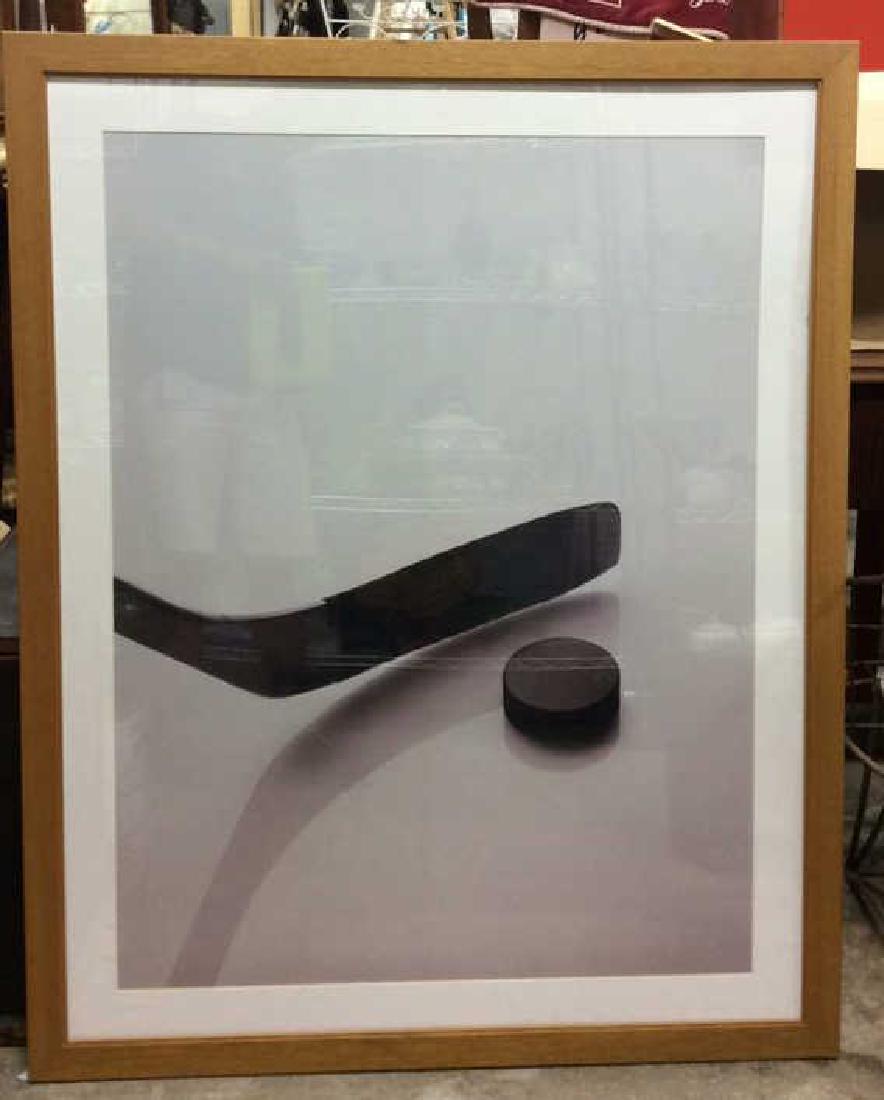 Matted Photographic Hockey Print: Matted photographic print depicts a hockey puck and a hockey stick on ice. Contains a tan wooden frame. Hockey, puck, stick, ice. Measures approx 48 inches tall x 38 inches wide.
