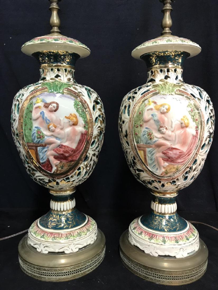 2 Capodimonte Ornate Porcelain Lamps: Pair Lamps are Porcelain, both have organically shaped pierced detail. Each contain intricately painted detail depicting 2 female figures and 1 cherub figure. Base is gold toned & brass. Both appears