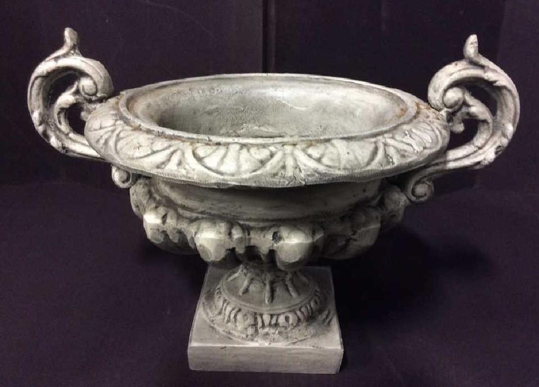 White Tone Weathered Planter Urn: White Tone Weathered Planter Urn. Faux stone with pedestal base and curled filigree handles. Faux stone dark with weathered style look. Some minor surface wear. Measures approx 30 in tall by 17 in lon