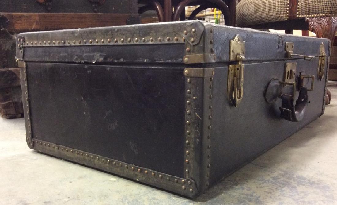Vintage Black Wood Valise Trunk Poss Leather Cover: Vintage black toned wooden trunk with poss leather cover. Trunk is designed with gold toned metal latches and front handle. Contains scratches. Measures approx 9 inches tall x 30 inches wide x 17 inch
