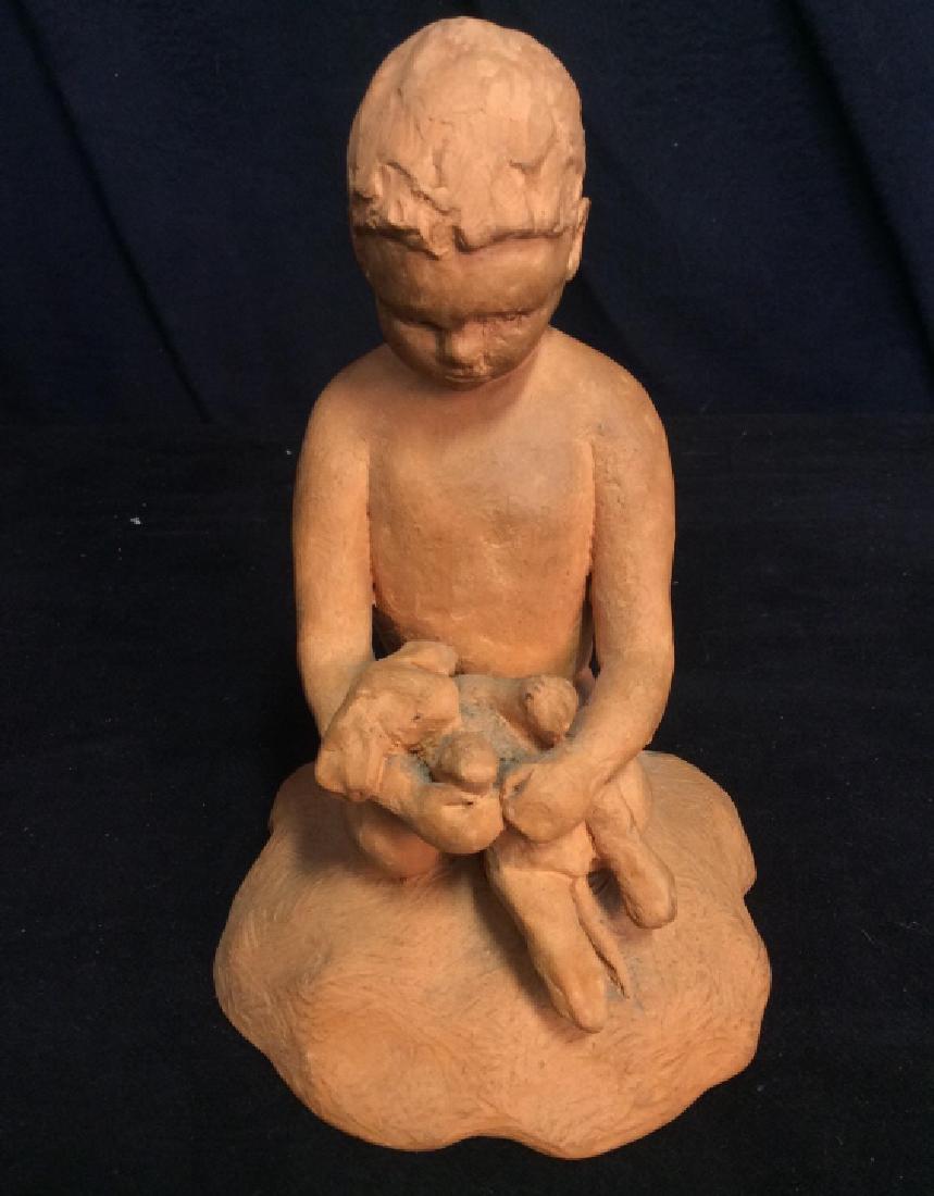 Clay Figurine Statue Signed PEG LEAVITT ‘61: Clay figurine statue is of a nude boy sitting on his knees with what appears to be a puppy laying on his knees with his arms wrapped around it. Signed on bottom of base Peg Leavitt ‘61. Contains som
