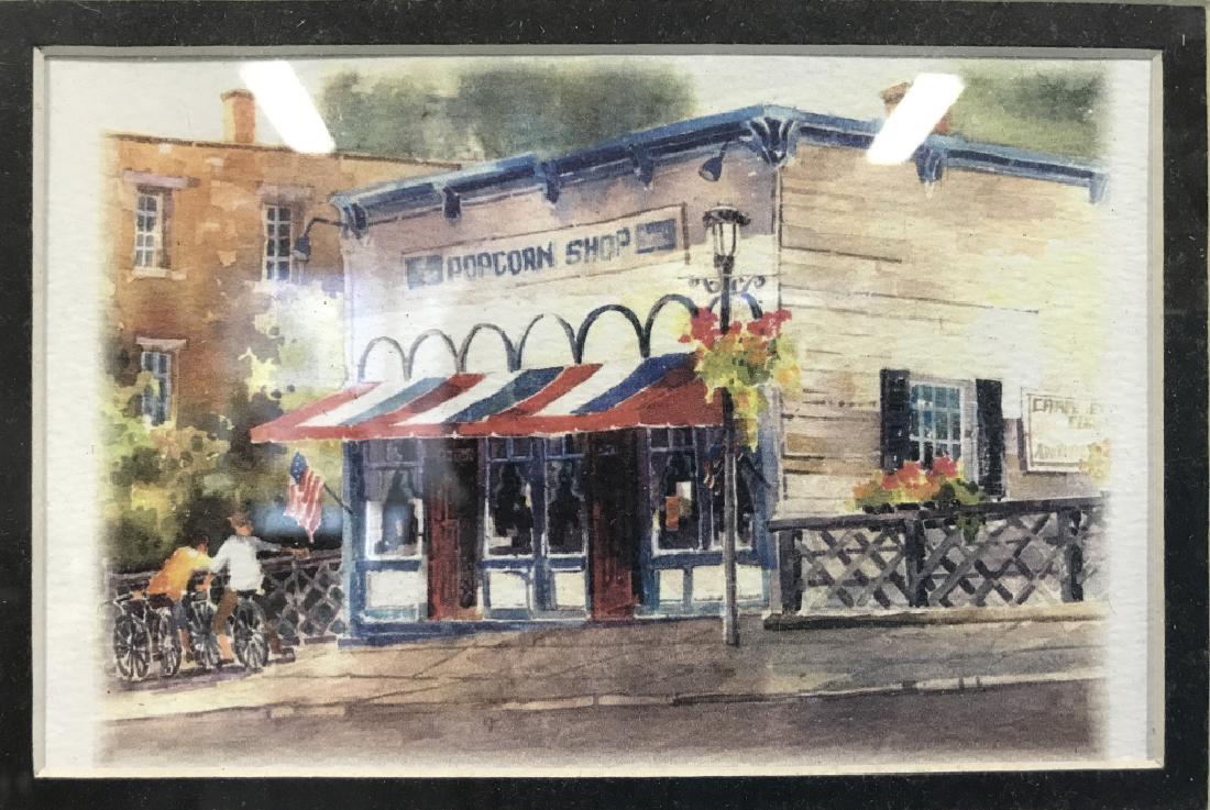 Four Town Attraction Site Matted Prints: Four matted prints of attraction sites of an American town. Prints depict the town center, a waterfall underneath a bridge, a local pop corn shop, and a gazebo. Contains a black toned wooden frame. Me