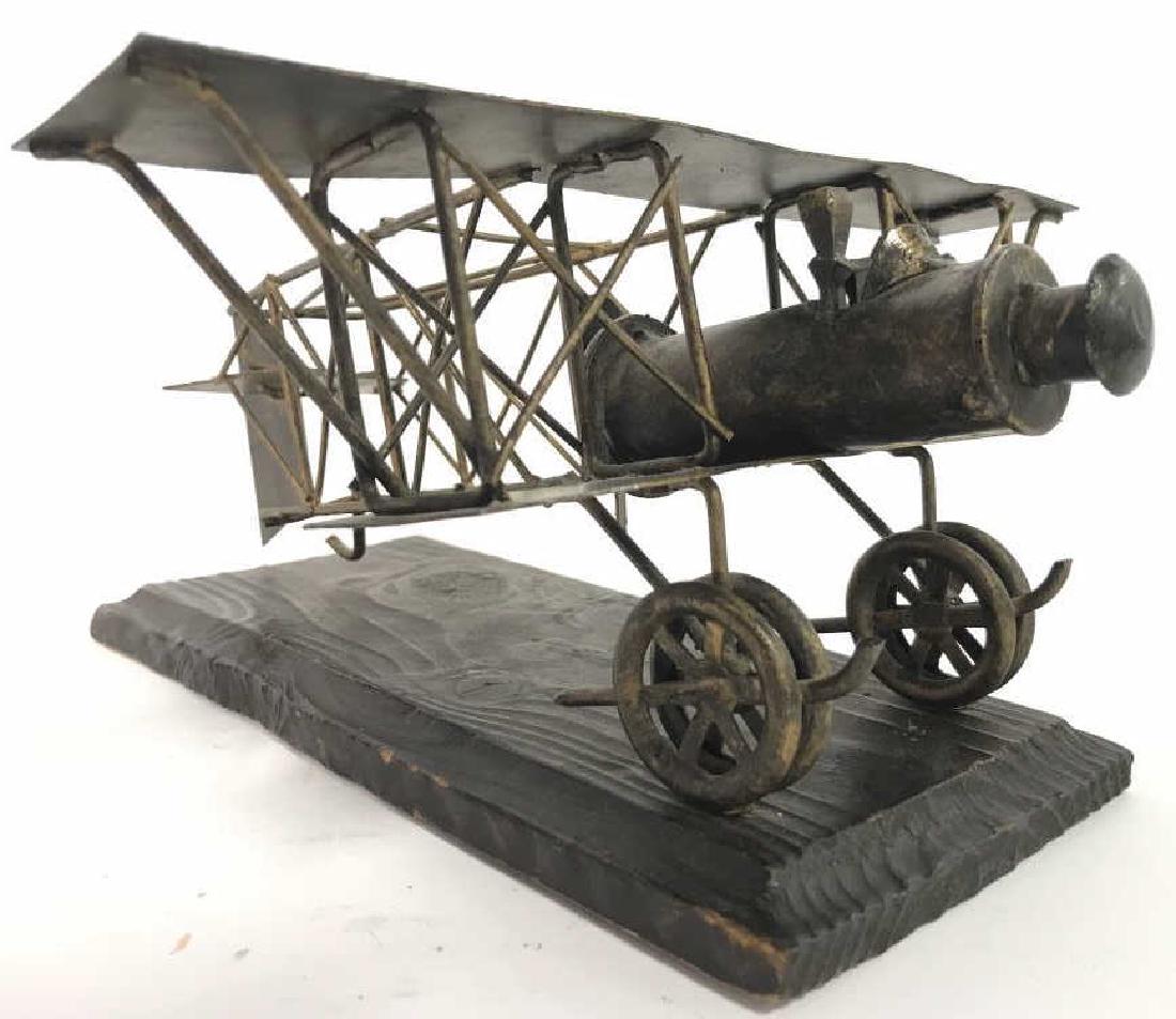 Gold Toned Metal Plane Figural W Wooden Base: Plane figural is gold toned and metal. Has brown toned wooden base. Depicts an antique plane. Measures approx 12 inches deep 10 inches wide, 5.5 inches tall. Table top decor, home decor, home accesory