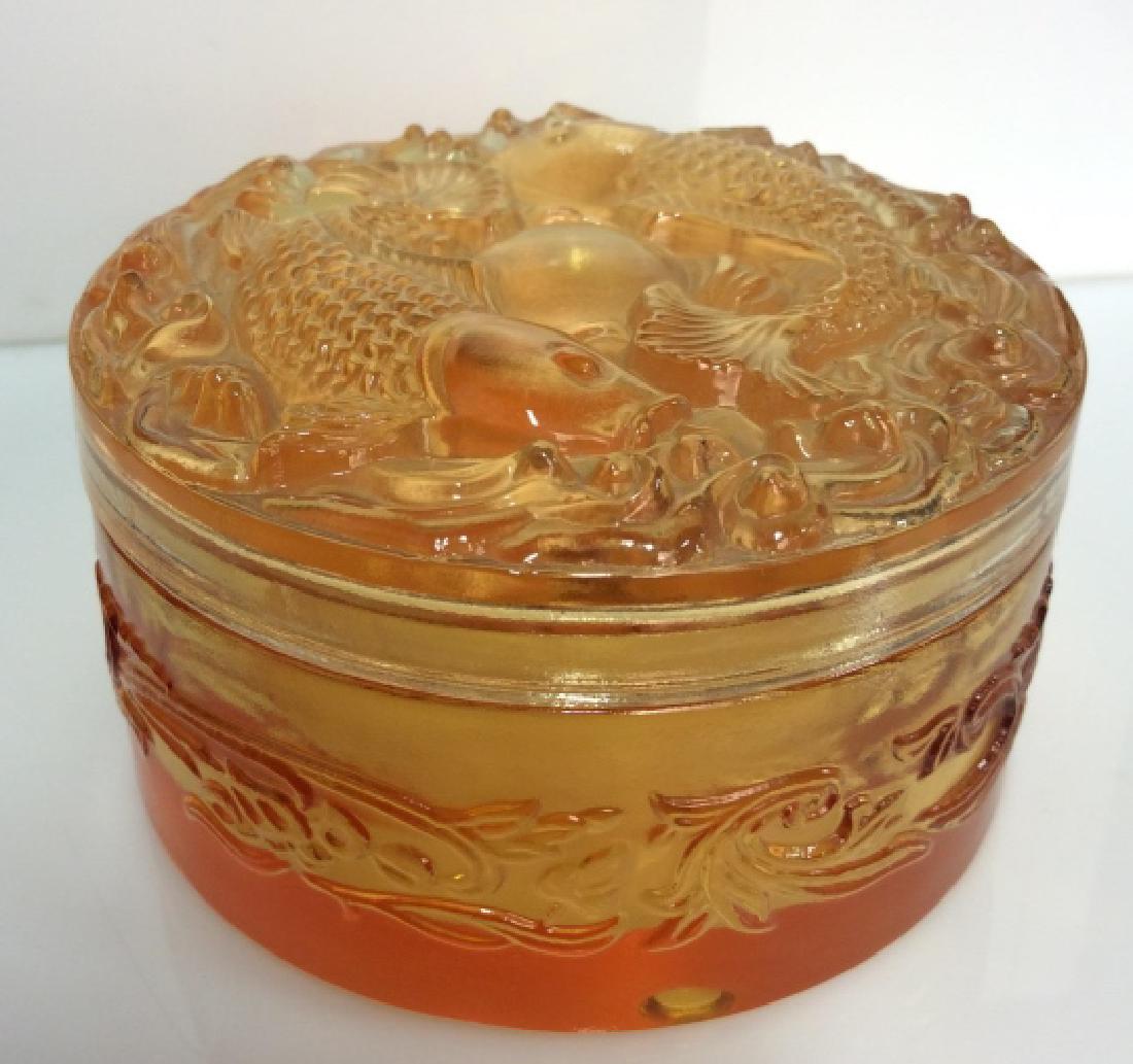 Orange Toned Art Glass Trinket Dish: Orange Toned Art Glass Trinket Dish. Lidded trinket dish with raised fish and wave design, dish is decorated with raised filigree design. Appears to be in good condition. Measures approx 2 1/2 in tall