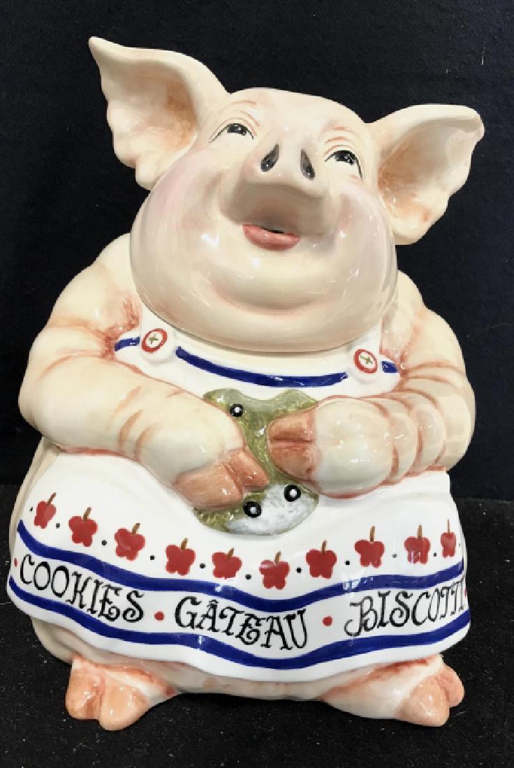JOANNE WEST TABLEAUX Pig Cookie Jar: Cookie jar is shaped like a like a pig wearing an apron eating a cookie. Reads JOANNE WEST TABLEAUX on underside. In good condition. Measures approx 9 by 7 in.