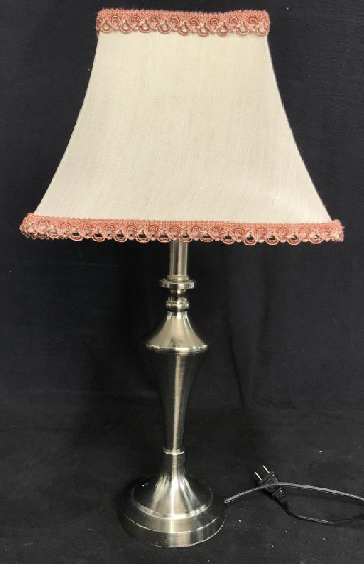 Silver Toned Metal Lamp W Shade: Lamp is silver toned and metal. Has tan toned shade with pink accents. Measures approx 20 inches tall 4.5 inches wide without shade. Lamp, vintage lighting, home decor.