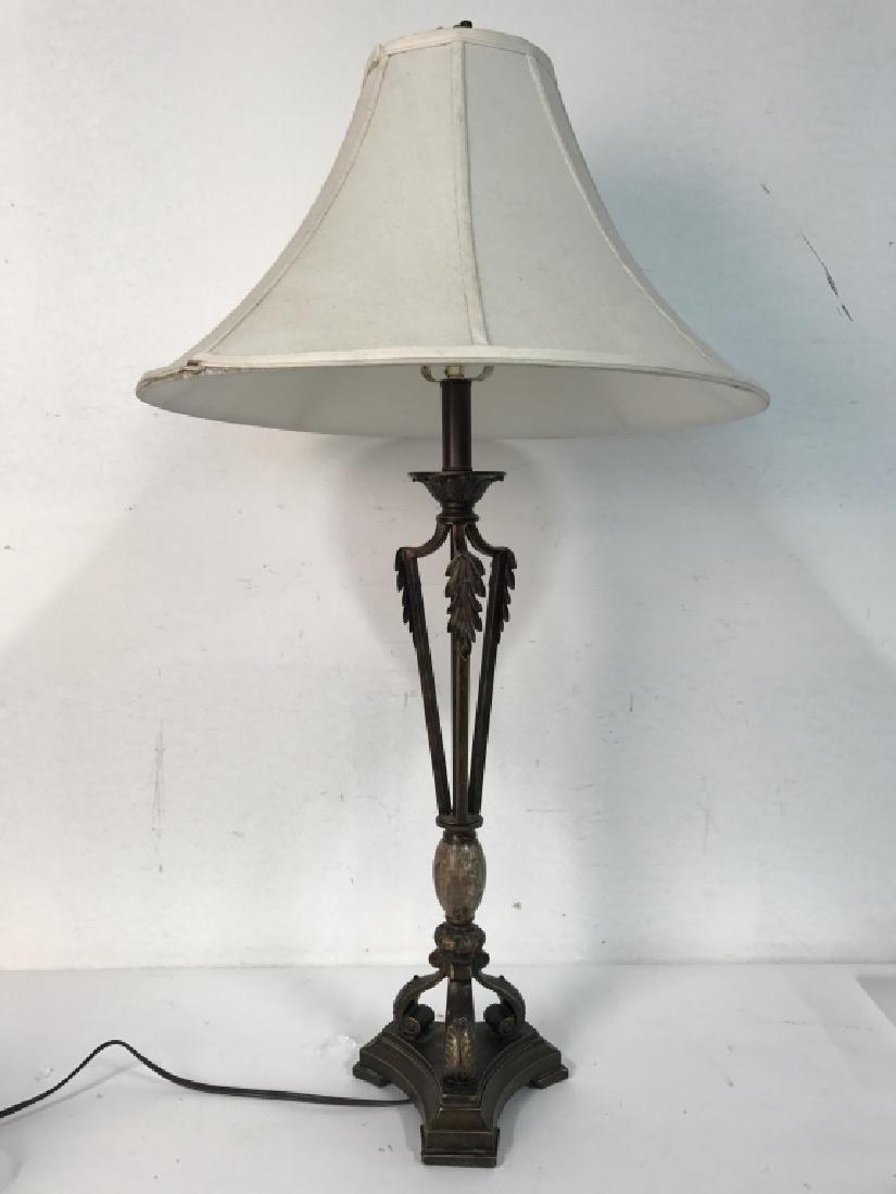 Bronze Toned Metal Lamp W Shade: Lamp is metal, contains leaf detail. Shade is cream toned. Has light brown toned egg shaped detail near base. Measures approx 37 inches tall 7 inches wide without shade. Includes finial.