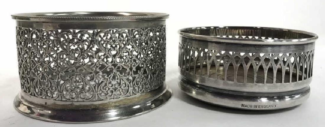 Lot 2 Silver Plated English Wine Coasters: Lot includes 2 silver plated wine coasters. Both have intricate pierced detail. One is marked ITALY. Both have emblems. Larger wine coaster measures approx 4 inches diameter 2.5 inches tall