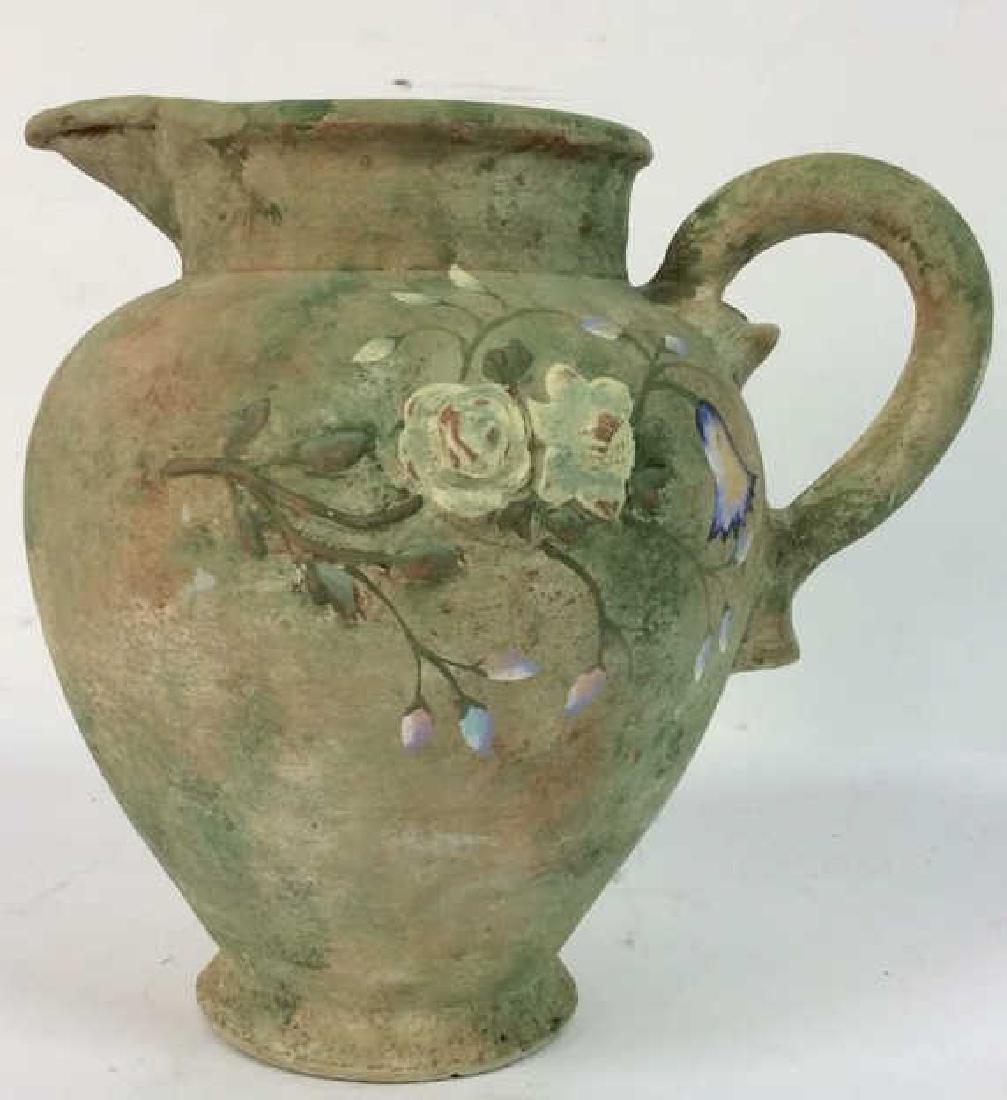 Green Toned Floral Detailed Ceramic Pitcher: Pitcher is green toned with multi toned floral detail including tones of blue, white,lavender and green. Contains what appears to be weathering and very minor chips. Measures approx 12 inches tall nd 