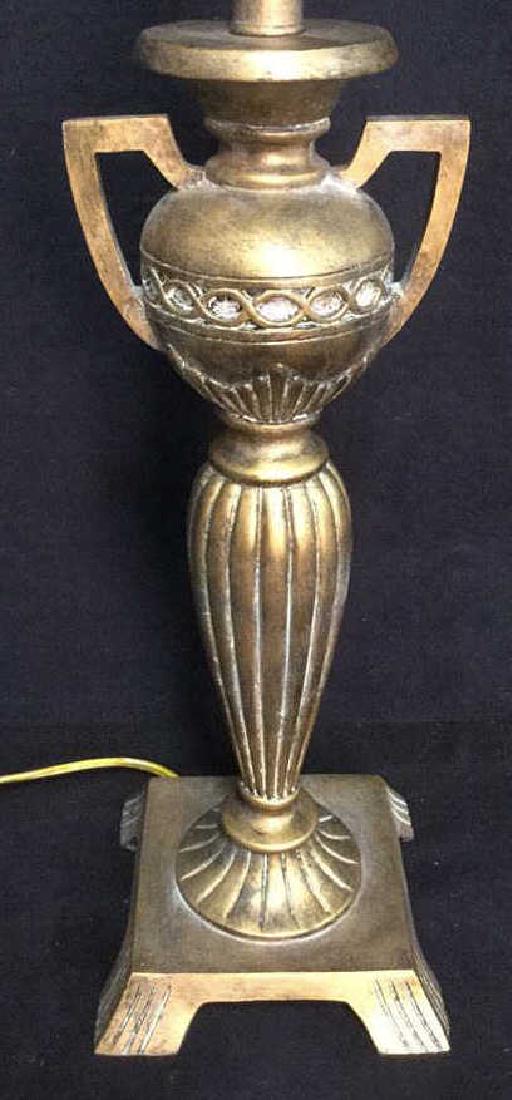 Gold Toned Trophy Lamp With Finial: Gold Toned Trophy Lamp With Finial. Lamp appears to be made out of a composite material that is carved into a dual handled trophy. Measures approx 31.5 inches tall x 7 inches wide. Some very small chi
