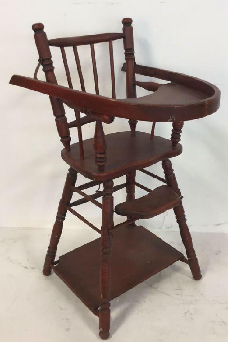 Wooden Red Toned Dolls Highchair: Wooden Red Toned Dolls Highchair possibly vintage. A red toned painted wooden highchair with flip top tray, spindled legs, back and arms. Some chips to paint and wood. Measures approx 28.5 inches tall