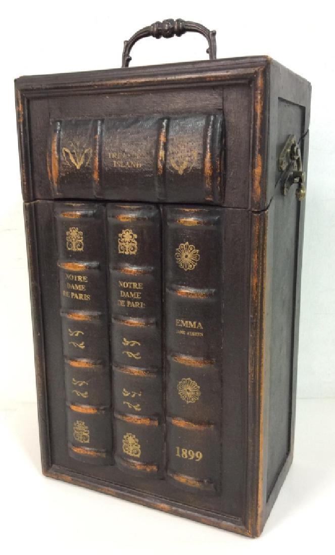 Wooden Wine Box W Book Spine Design: Wooden Wine Box W Book Spine Design. Black toned painted wood with book spine design and gold toned details. Dark toned handle and lock on side. Felt fabric lined interior. Measures approx 16 in tall 