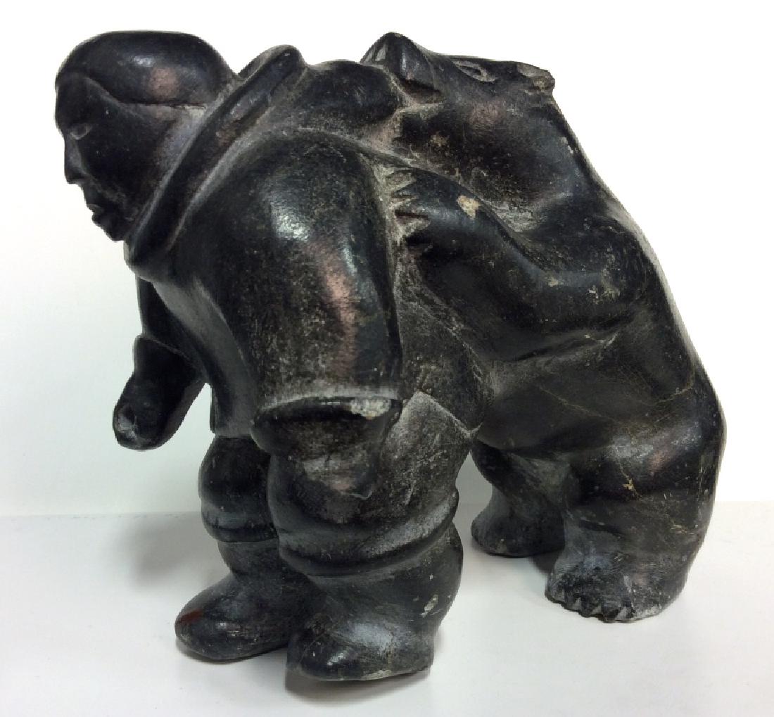 Inuit Style Carving Man And Bear: Inuit Style Carving Man And Bear. Black toned natural stone carved statuette depicting Inuit man being attacked by bear, damage to hand, some other surface wear. Measures approx 6 in tall by 6 in long