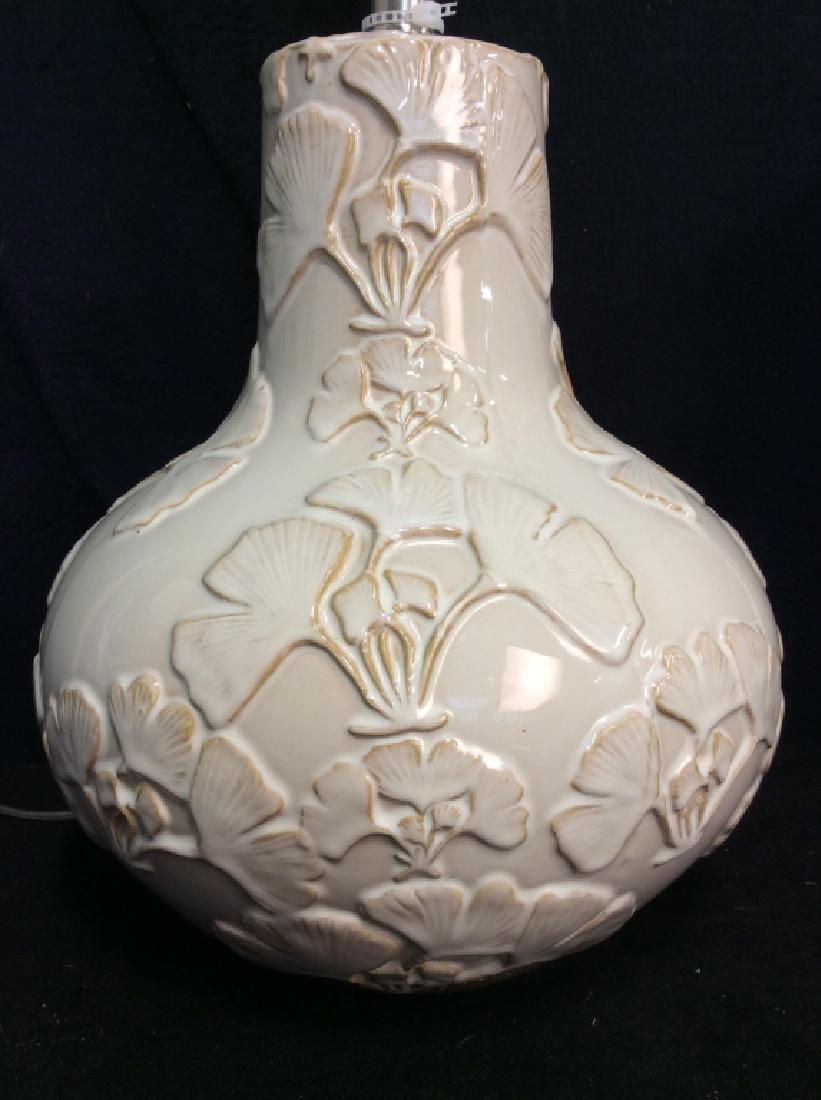 White Toned Porcelain Ginkgo Leaf Decorated Lamp: White Toned Porcelain Ginkgo Leaf Decorated Lamp. Oblong porcelain body with raised dimensional ginkgo leaf pattern, with harp, finial and shade. Measures approx 25 in tall with harp by 10 in in diame