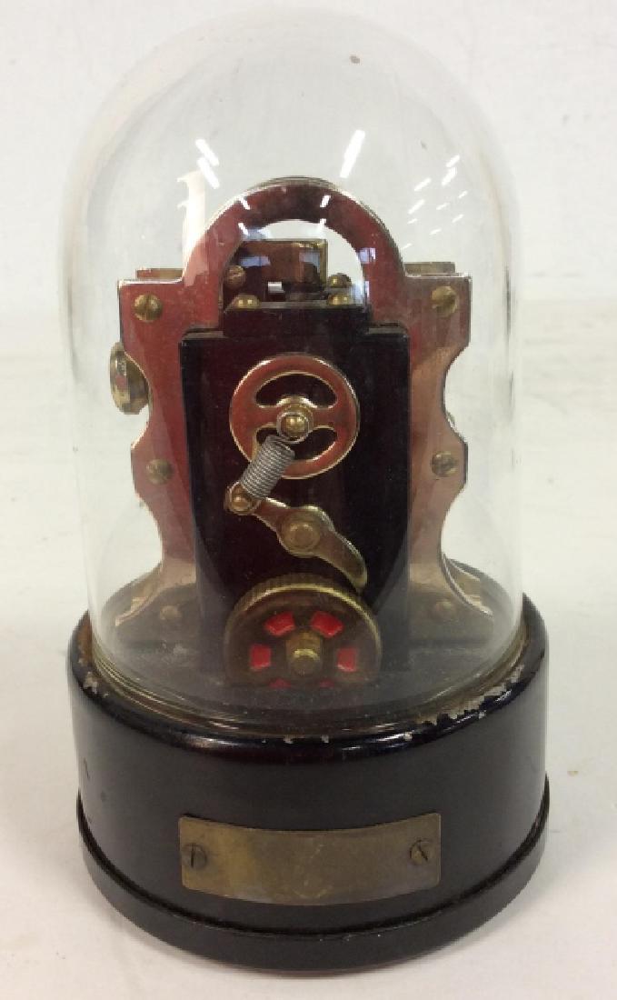 Decorative Cigarette Lighter in glass case: Decorative cigarette lighter in a glass domed case, the lighter set on a black add and covered by a glass dome, Not tested, approx dimensions5 1/2 x 3 1/2 in, scratches to the base, plaque not inscrib