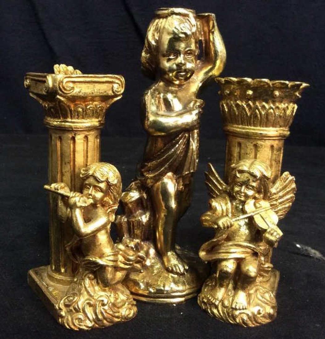 3 Gold Toned Cherub Candlesticks: Two are gold painted composite with musical instruments and cherubs , putties, angles, taller is ormolu Metal Gilded Metal measures app 6.5 inches, putti Cherub form, one angel broken wings